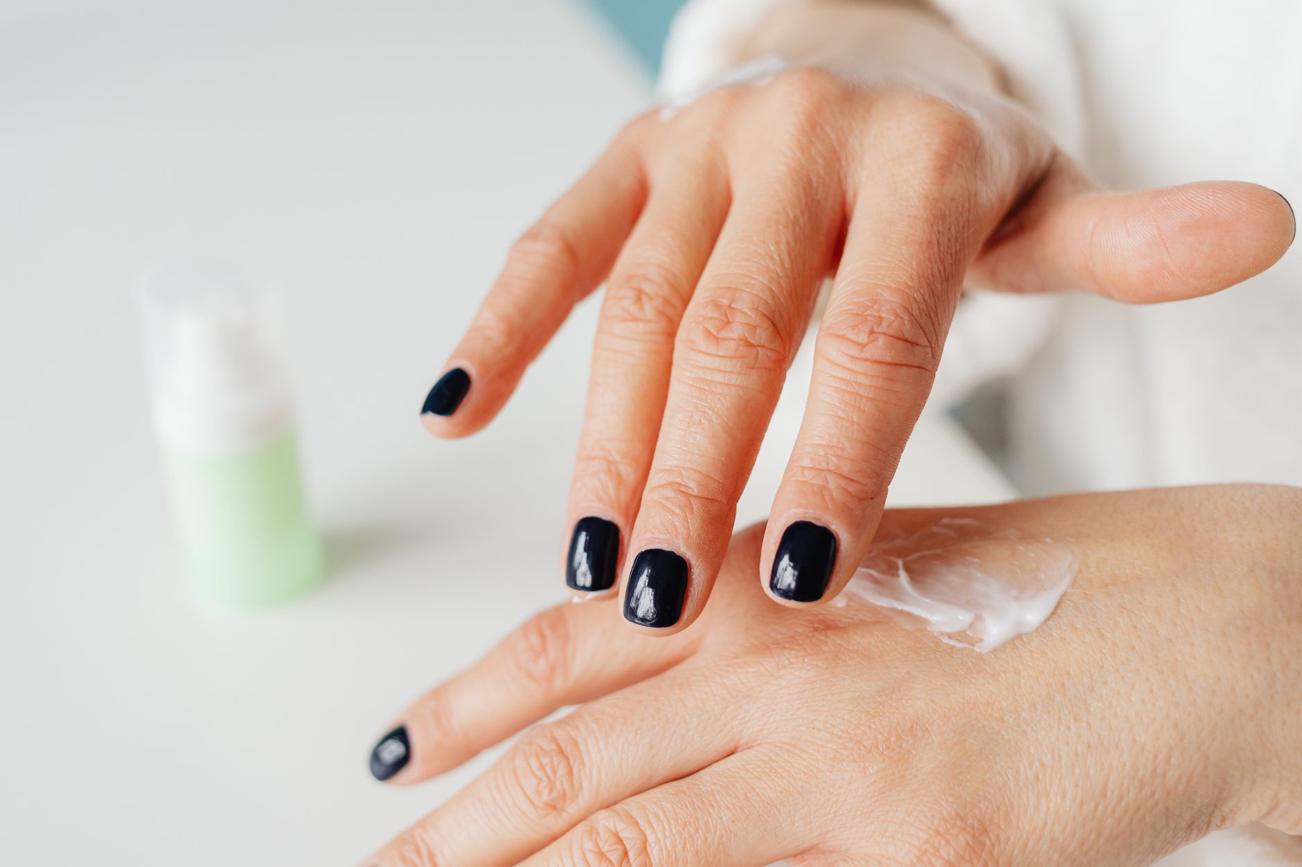 Close-up of a woman applying hand cream for moisturizing.